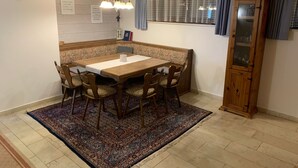 Un coin repas comprenant une table en bois, des chaises, un tapis à motifs, une horloge et un meuble.
