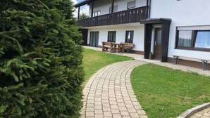 Un bâtiment avec un chemin pavé menant à un espace aménagé avec des bancs.