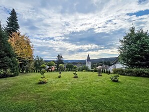 Un jardin bien entretenu, agrémenté de divers arbustes, avec une église en arrière-plan.