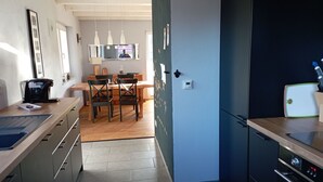 Una cocina moderna con refrigerador, horno y una mesa de comedor de madera con sillas.