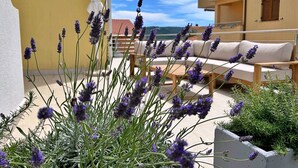A balcony with lavender plants, a white umbrella, and a beige sofa. - Apartment PintaDeSol by Interhome (Krk/Čižići)