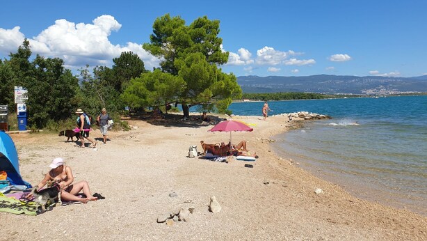 A beach with people relaxing, a tent, and a clear view of the sea and mountains. - Apartment PintaDeSol by Interhome (Krk/Čižići)