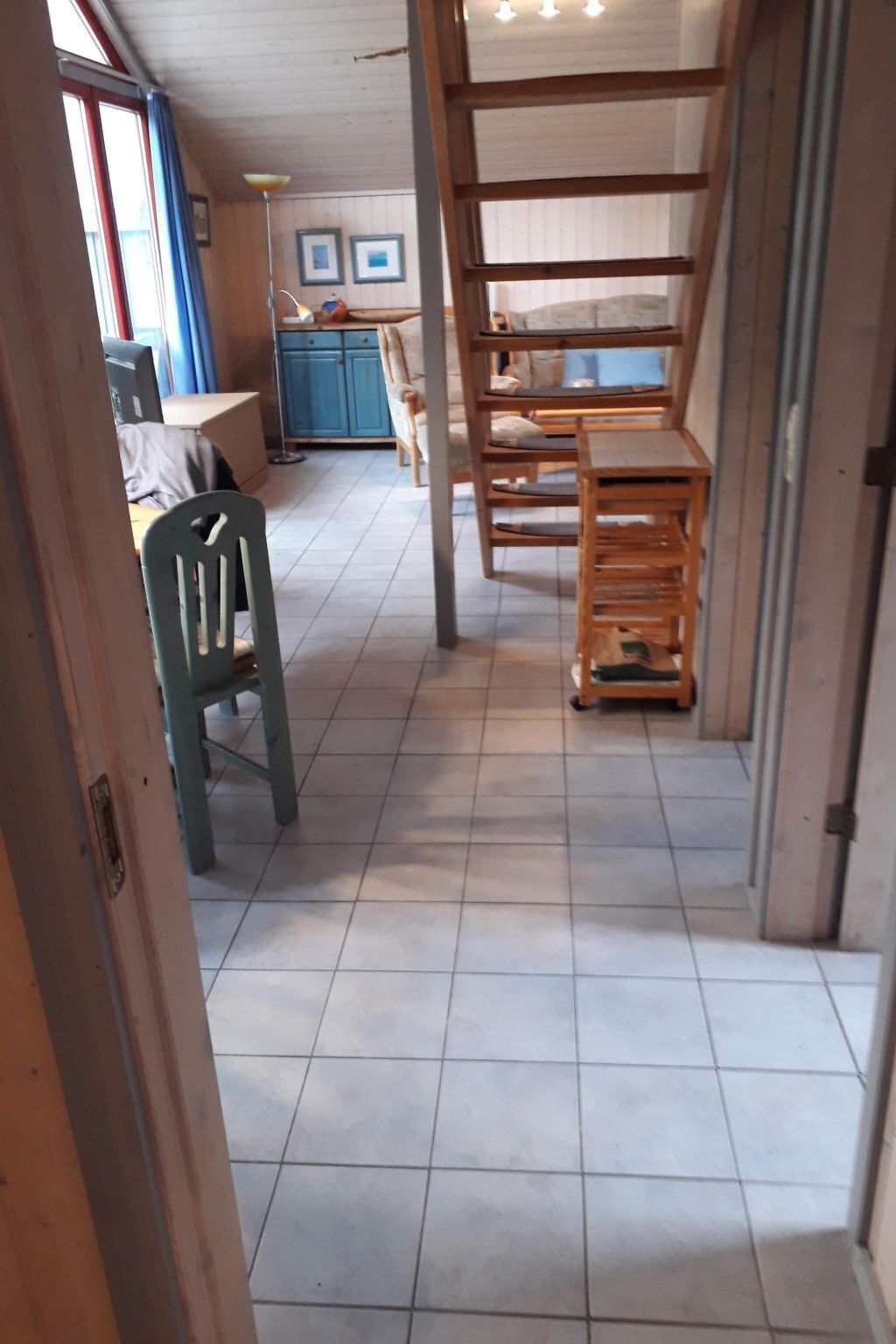 Käytävä, jossa on laatoitettu lattia, puiset huonekalut ja taustalla sininen kaappi.