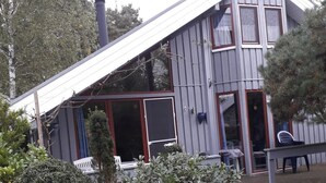 Et toetagers hus med skråtag, store vinduer og en terrasse.