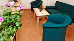 A living room with a green sofa, a wooden coffee table, and a lamp. There is a TV on a stand and a potted plant with pink flowers. - Beim Kahnfährmann by Interhome (Schlepzig)