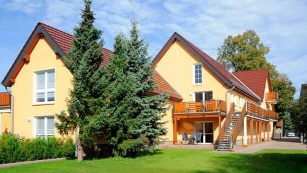 A yellow building with a red roof, a staircase, and a small balcony. - Beim Kahnfährmann by Interhome (Schlepzig)