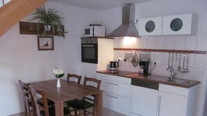 A compact kitchen with a wooden dining table, white cabinets, and a built-in oven. - - Uns lütt Hüsung by Interhome (Löwenberger Land)