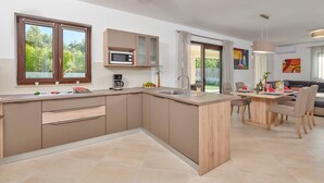 Una cucina moderna con isola centrale, elettrodomestici integrati e zona pranzo con tavolo e sedie.