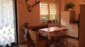 A cozy kitchen with a wooden table and chairs, a refrigerator, and a window with blinds. - in Neustrelitz mit Garten und Grill by Interhome (Neustrelitz)