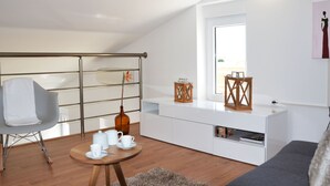 A modern loft apartment with a high ceiling, a dining area with a round wooden table, a grey sofa, and a white kitchenette. - mit Blick auf das Wasser by Interhome (Poreč/Nova Vas)