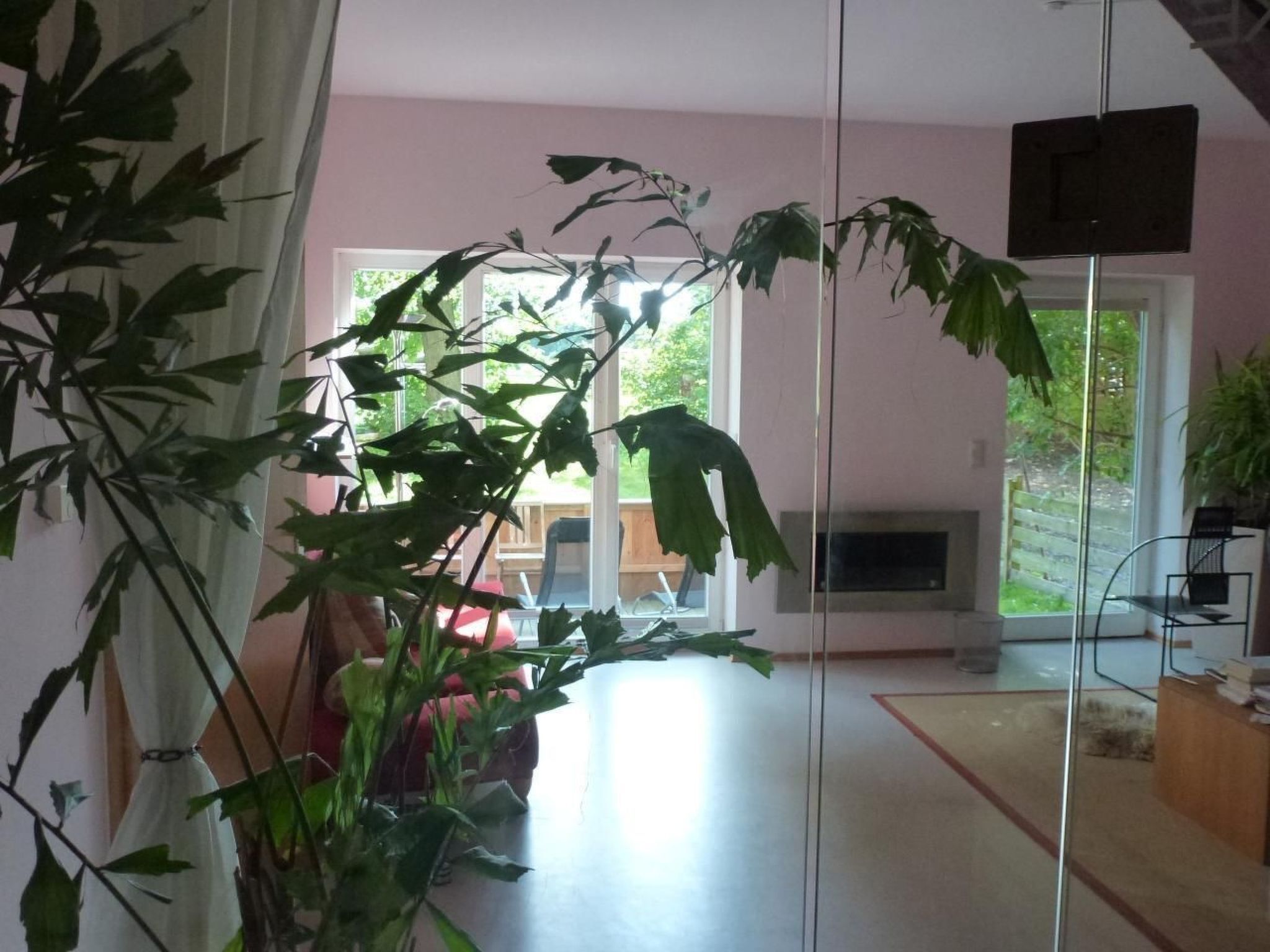 A room with a large window, a flat-screen TV mounted on the wall, and a wooden floor.