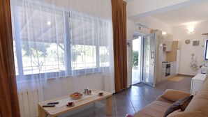 A living room with a sofa, a coffee table with a fruit bowl, and a kitchen in the background. - Zweizimmerwohnung mit großer Terrasse in Grupija by Interhome (Umag/Savudrija)