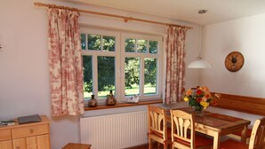 A cozy dining area with a wooden table and chairs, a window with curtains, and a radiator below. - in Göhren mit Eigener Terrasse by Interhome (Barnin)