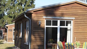 A wooden house with a large window and a patio with chairs and a table. - in Göhren mit Eigener Terrasse by Interhome (Barnin)