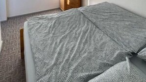 Ett sovrum med en säng, en garderob i trä, en spegel och en tv på väggen.