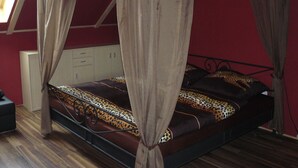 Ein Himmelsbett mit Leopardenmuster, Holzboden und einer roten Wand.