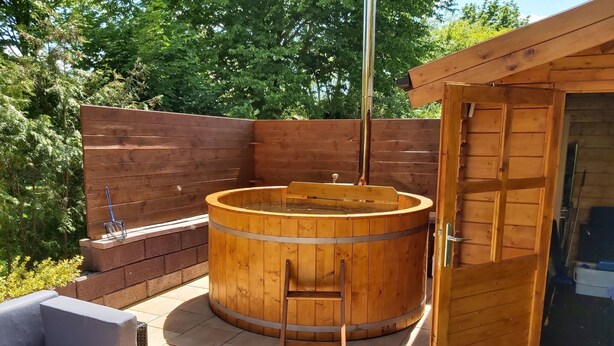 Eine Holzsauna mit einer Leiter, einer hölzernen Sitzbank und einer Glastür.
