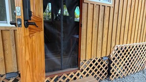 A wooden door with a sliding glass panel, a small porch with a wooden bench, and a lattice fence.