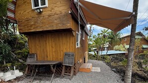Ett trähus med ett böjt tak, ett litet fönster och en uteplats med ett bord och stolar.