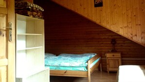 Une chambre dans un chalet en bois, avec un lit en mezzanine, une petite table de chevet et une armoire.