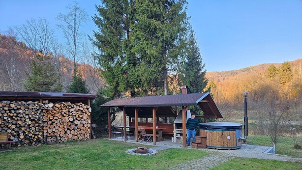 Un cadre extérieur rustique avec une structure en bois, un jacuzzi et une pile de bois de chauffage.
