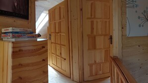 Um quarto com teto inclinado, guarda-roupa de madeira e uma televisão fixada na parede.