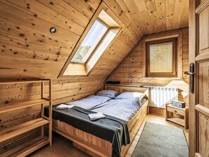 A wooden cabin with a loft bedroom, a window, a radiator, and a door.
