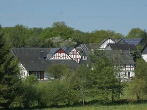 A row of traditional half-timbered houses with solar panels on the roofs, surrounded by greenery. - Göttert by Interhome (Dickenschied)