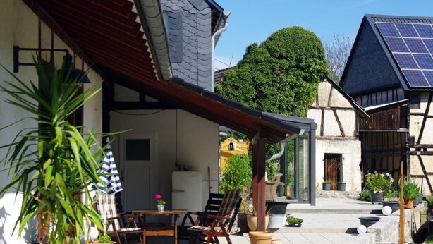 A patio with outdoor furniture, potted plants, and a building with solar panels. - Göttert by Interhome (Dickenschied)
