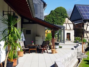 A patio with outdoor furniture, potted plants, and a building with solar panels. - Göttert by Interhome (Dickenschied)