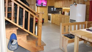 A wooden staircase leading to a kitchen with wooden cabinets, a refrigerator, and a television in the background. - Chata Martina A by Interhome (Zdiar)