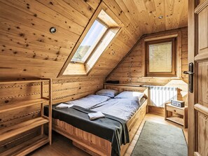 A wooden cabin with a loft bedroom, a built-in bench, a window, and a radiator.