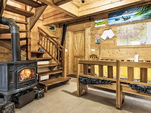 A wooden interior with a fireplace, wooden staircase, and a bench.