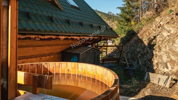 A wooden cabin with a sloped roof, a wooden hot tub, and a view of a forested hillside. - Chata Martina A by Interhome (Zdiar)