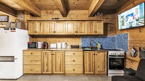 A kitchen with wooden cabinets, a microwave, a toaster, a kettle, and a stove. - Chata Martina A by Interhome (Zdiar)