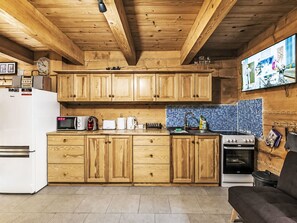 A kitchen with wooden cabinets, a microwave, a toaster, a kettle, and a stove.
