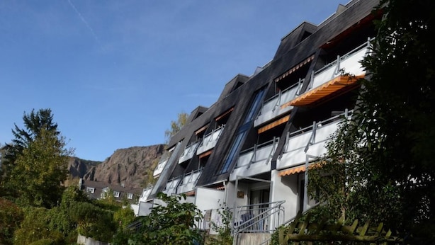 Un bâtiment moderne doté de nombreux balcons, d’un escalier et offrant une vue sur un paysage montagneux.