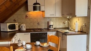 Uma cozinha acolhedora com vigas de madeira, uma mesa de jantar com cadeiras e uma pequena ilha com pia.