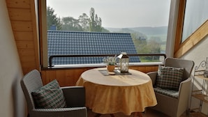 A cozy balcony with wicker chairs, a round table, and a view of a blue-roofed building. - Elztalblick by Interhome (Bereborn)
