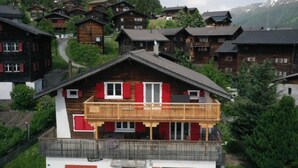 A chalet-style house with a balcony, surrounded by other similar houses in a mountainous area. - Alter Konsum by Interhome (Bellwald)