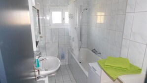 A bathroom with a toilet, sink, and bathtub. - Alter Konsum by Interhome (Bellwald)