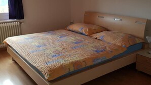 A single-bed room with a wooden headboard, a patterned bedspread, and a bedside table with a lamp. - Alter Konsum by Interhome (Bellwald)