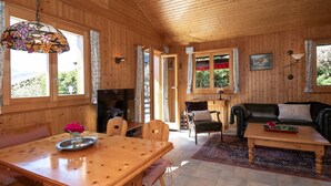 L’intérieur d’un chalet en bois comprend une table à manger, des chaises, un canapé et un téléviseur.