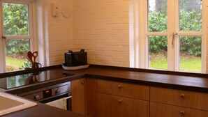 A kitchen with wooden cabinets, a black countertop, and a window with a view of greenery. - Haus Siedschelje by Interhome (Schwanewede)
