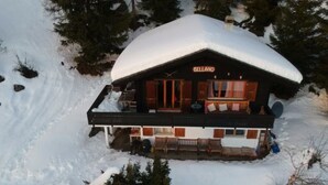 Ein schneebedecktes Chalet namens 'BELLAND' mit Balkon und Außenbereich.