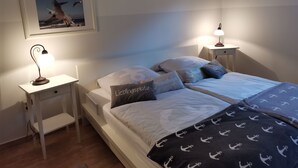 A neatly made bed with pillows, a bedside lamp, and a framed picture on the wall. - Apartment Ole by Interhome (Oldenburg in Holstein)