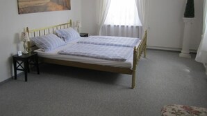 Una camera da letto con un letto, un comodino, una lampada, un quadro, una finestra con tende e una pianta in vaso.