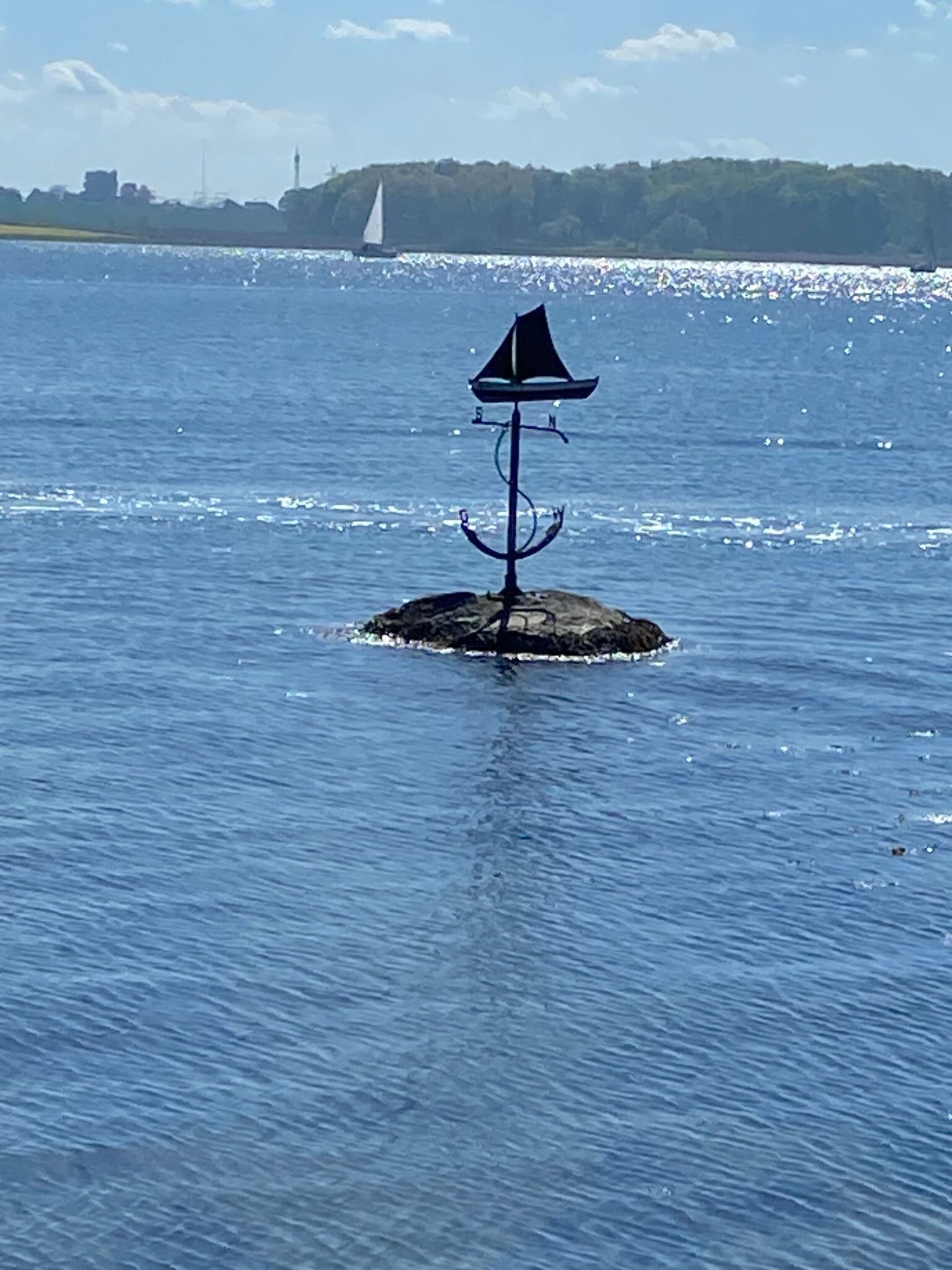 Una pequeña isla con un indicador de viento único en medio de una masa de agua tranquila.