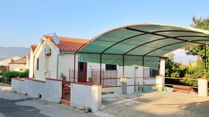 Uma casa com varanda coberta, telhado de telhas vermelhas e fachada branca.
