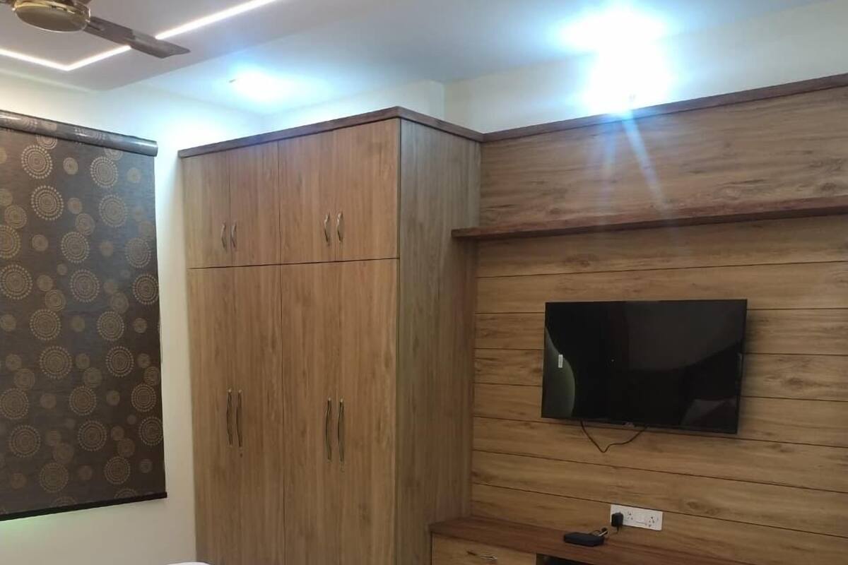 Ένα υπνοδωμάτιο με κρεβάτι, ξύλινη ντουλάπα, τηλεόραση και εντοιχισμένους αποθηκευτικούς χώρους.
